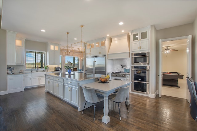 kitchen featuring stainless steel appliances, a kitchen island, white cabinetry, and custom exhaust hood