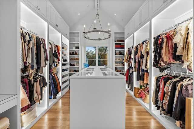 spacious closet with a chandelier, light hardwood / wood-style floors, and lofted ceiling