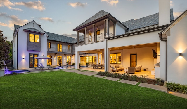 back of property featuring outdoor lounge area, a balcony, a patio area, and a lawn