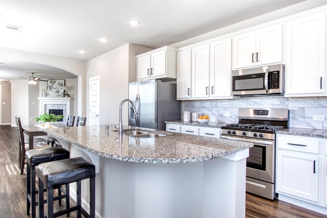 kitchen featuring white cabinetry, dark wood-type flooring, light stone counters, and appliances with stainless steel finishes