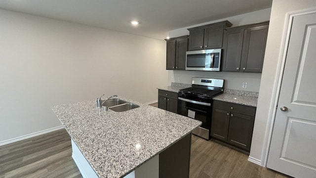 kitchen with sink, stainless steel appliances, a kitchen island with sink, and dark hardwood / wood-style floors