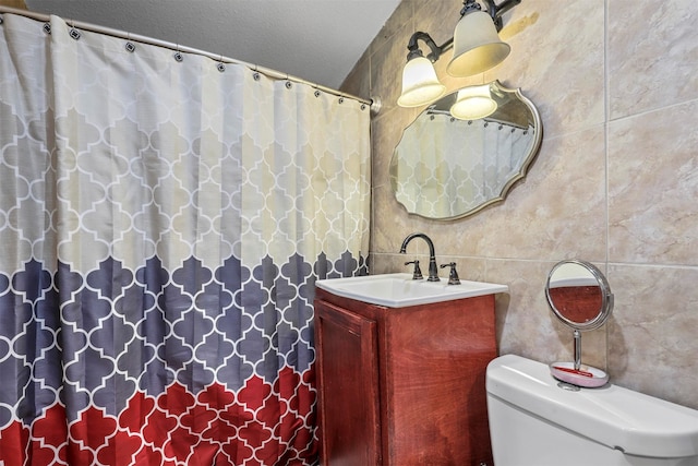 bathroom with vanity, toilet, and tile walls