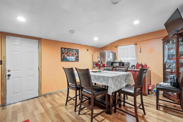 dining space with vaulted ceiling and light hardwood / wood-style flooring