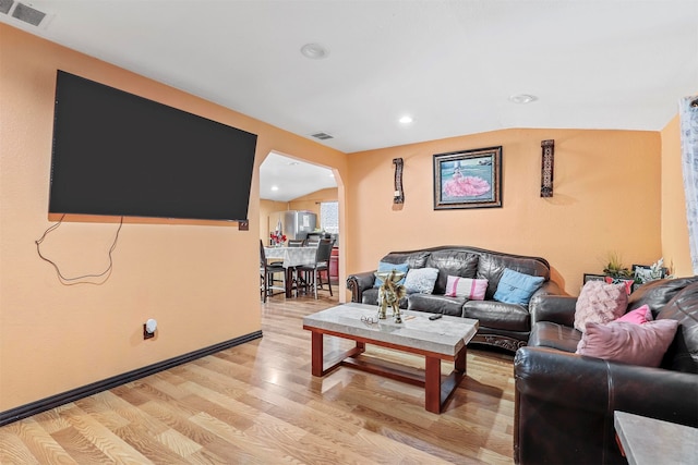 living room with light hardwood / wood-style floors and vaulted ceiling