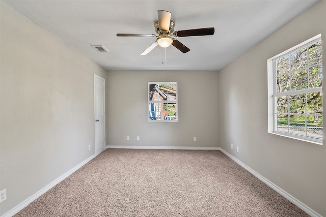 spare room with ceiling fan, plenty of natural light, and carpet