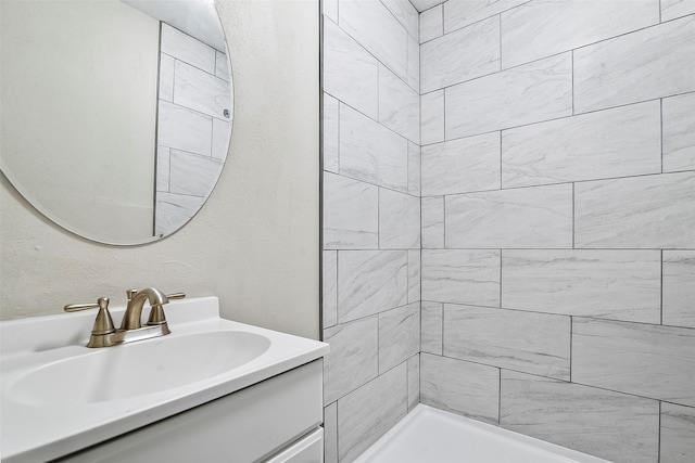 bathroom with a tile shower and vanity