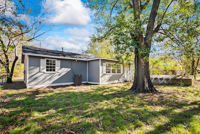 rear view of property featuring a lawn and central AC unit