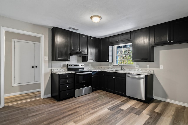 kitchen with light stone countertops, appliances with stainless steel finishes, a textured ceiling, and dark wood-type flooring