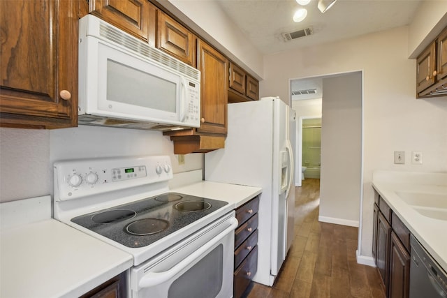 kitchen with dark wood-style floors, light countertops, white appliances, and visible vents