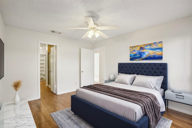 bedroom featuring a ceiling fan, wood finished floors, visible vents, and baseboards