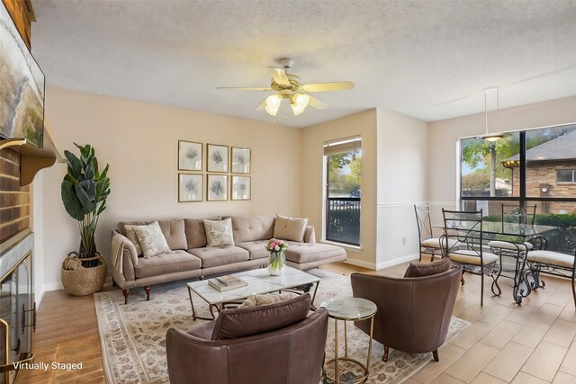 dining area with ceiling fan, a fireplace, a textured ceiling, and light wood-type flooring