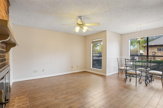 dining area featuring wood-type flooring, a textured ceiling, and ceiling fan