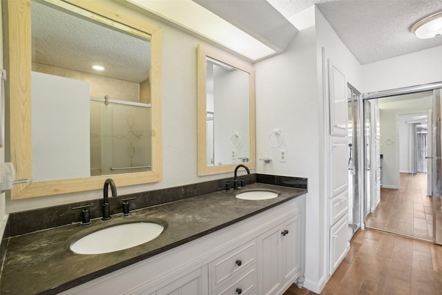 full bathroom with a sink, a textured ceiling, and wood finished floors