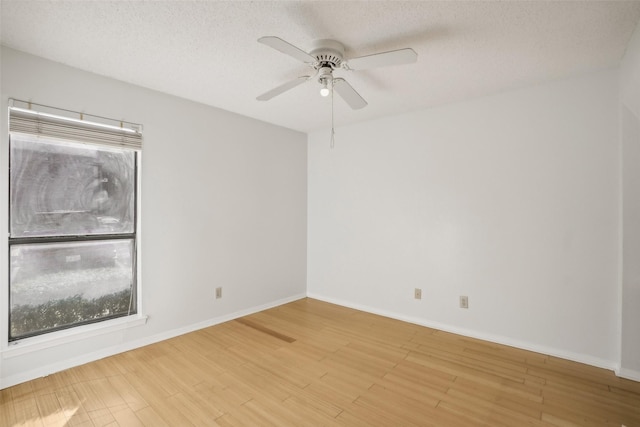 unfurnished room with light wood-type flooring, ceiling fan, a textured ceiling, and baseboards