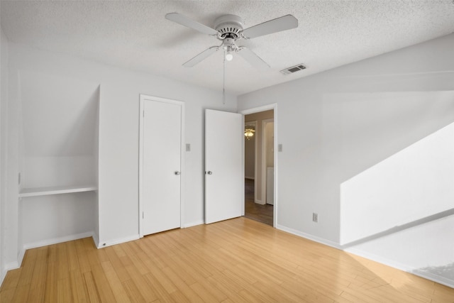 unfurnished bedroom featuring visible vents, light wood-style flooring, ceiling fan, a textured ceiling, and baseboards