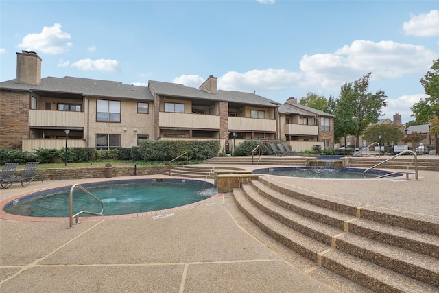 view of swimming pool featuring a hot tub and a residential view