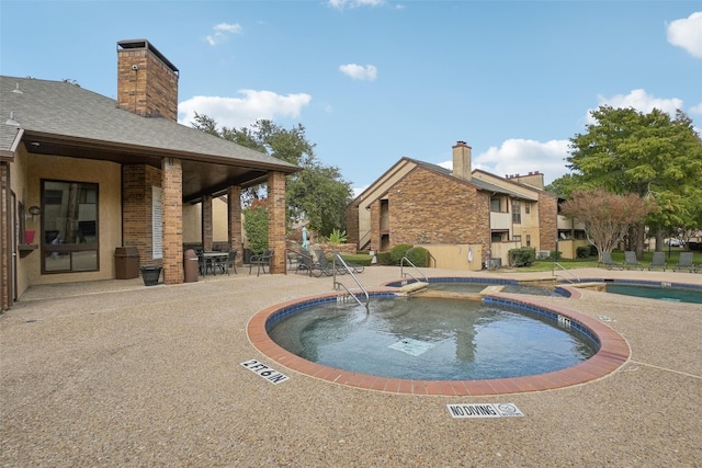 community pool featuring a patio area and a hot tub