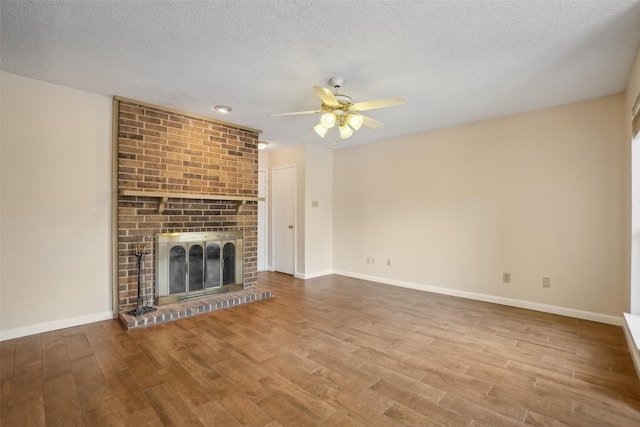 unfurnished living room featuring a brick fireplace, ceiling fan, baseboards, and wood finished floors