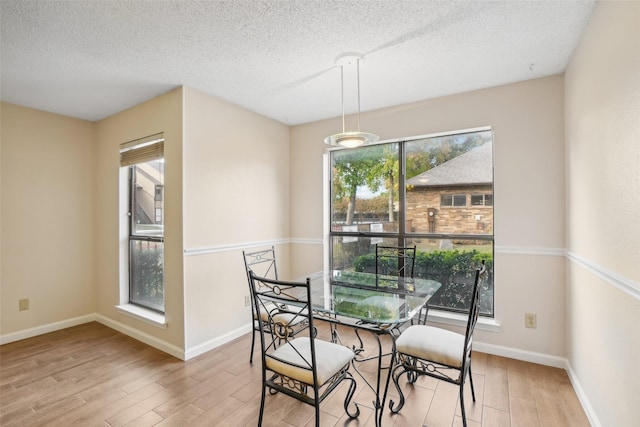 dining space with light wood finished floors, baseboards, and a textured ceiling