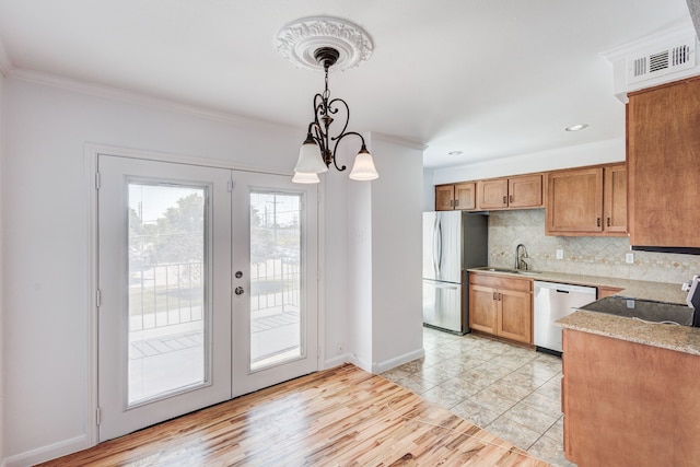 kitchen with french doors, light wood-type flooring, ornamental molding, stainless steel appliances, and pendant lighting