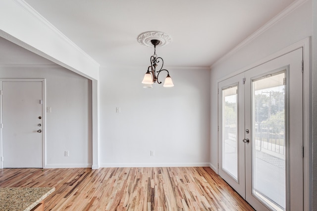 unfurnished dining area featuring light hardwood / wood-style floors, an inviting chandelier, and ornamental molding