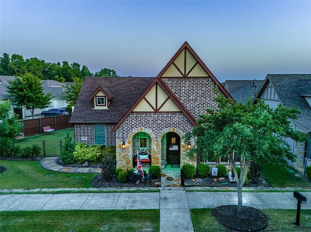 tudor house featuring a porch and a lawn