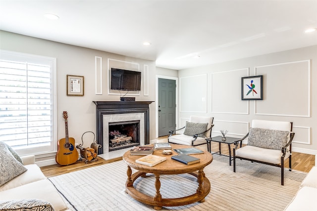 living room featuring a healthy amount of sunlight, a high end fireplace, and light wood-type flooring