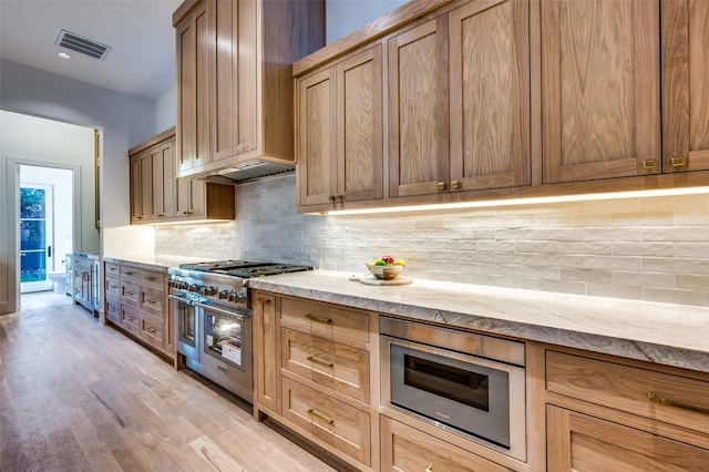 kitchen featuring stainless steel appliances, tasteful backsplash, light hardwood / wood-style floors, and custom exhaust hood