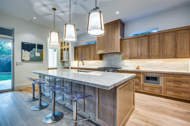 kitchen with hanging light fixtures, a large island, light hardwood / wood-style floors, a kitchen bar, and stainless steel appliances