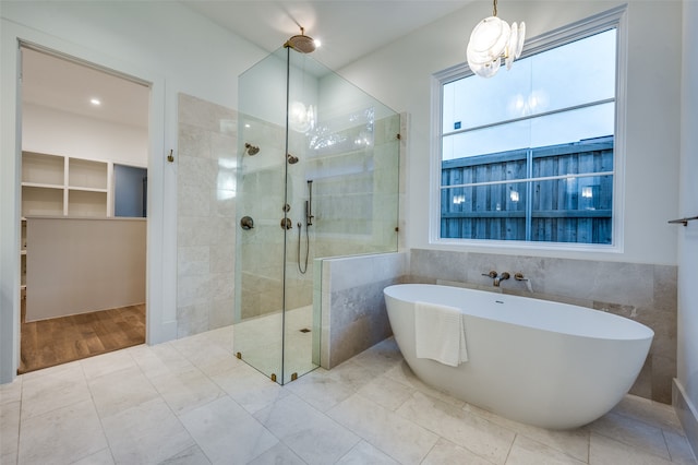 bathroom featuring wood-type flooring, tile walls, plus walk in shower, and a chandelier