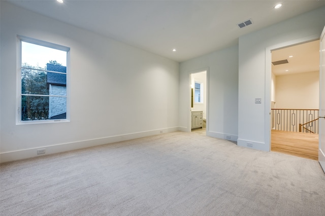 unfurnished bedroom featuring connected bathroom and light colored carpet