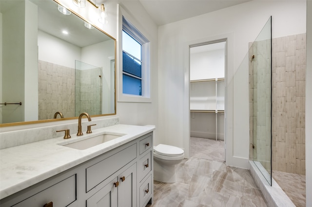 bathroom featuring a tile shower, vanity, and toilet