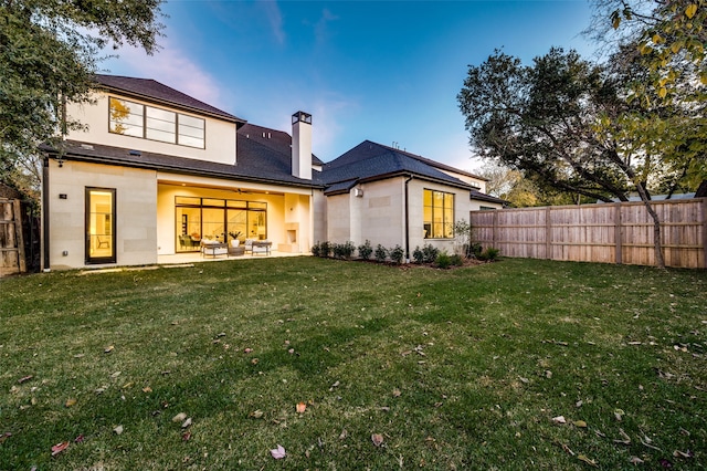 back house at dusk with a yard and a patio