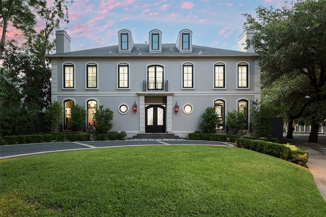 french country inspired facade featuring a yard and french doors