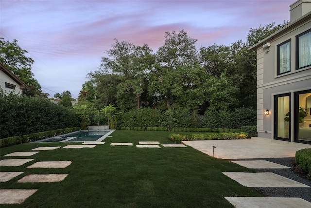 yard at dusk featuring a patio