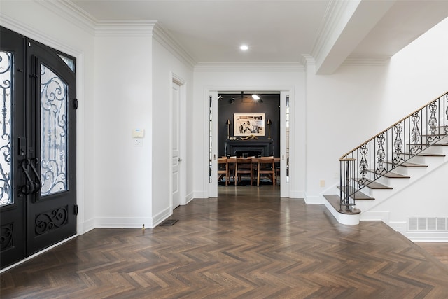 entryway with dark parquet flooring and ornamental molding