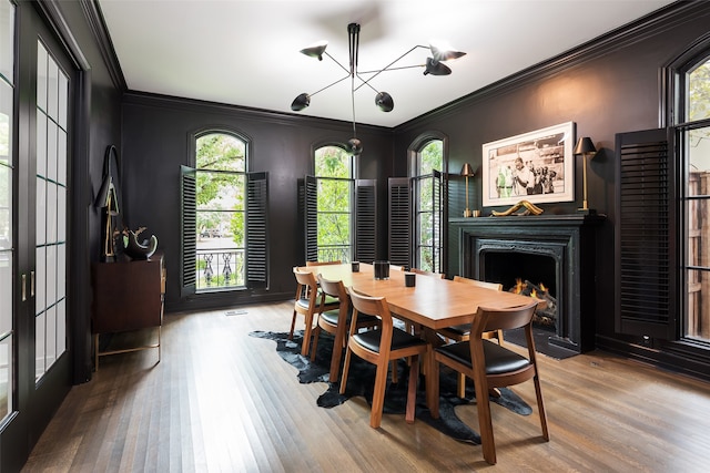 dining space featuring hardwood / wood-style floors, crown molding, and an inviting chandelier