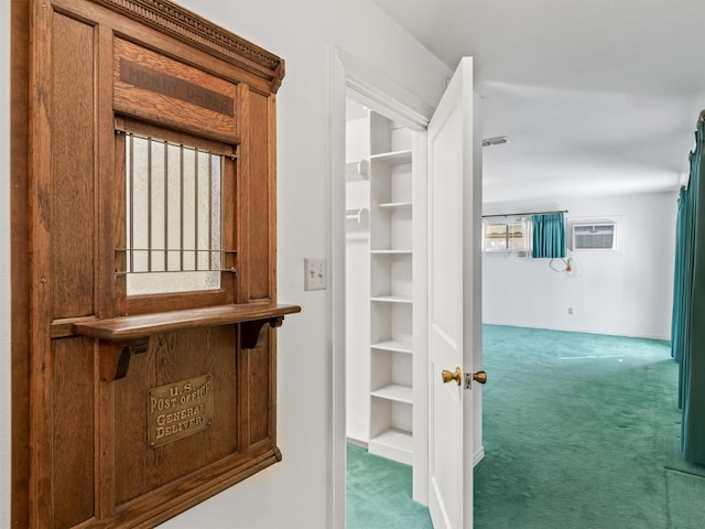 hall featuring a wall mounted air conditioner and dark colored carpet