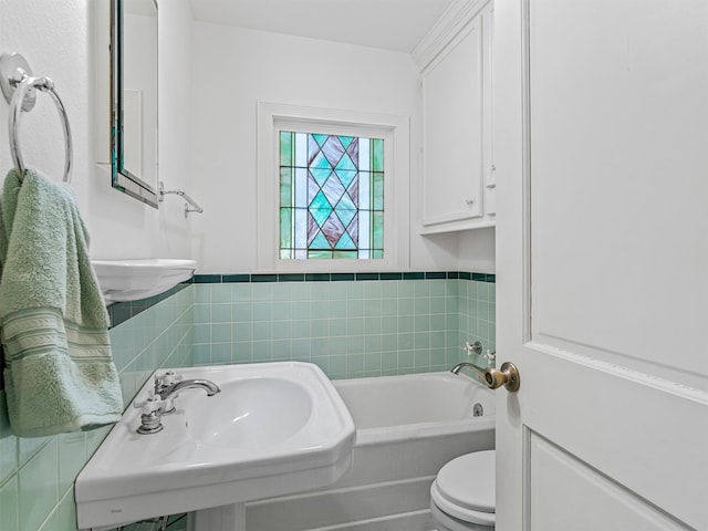 bathroom with a bathing tub, sink, tile walls, and toilet