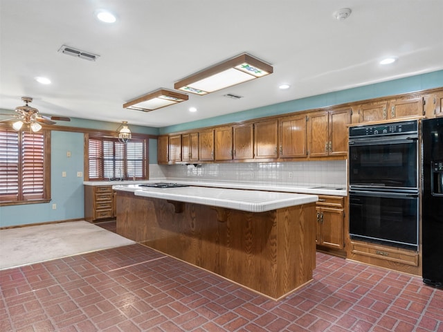 kitchen featuring tasteful backsplash, a kitchen breakfast bar, a center island, ceiling fan, and black appliances