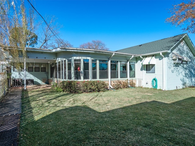 rear view of house with a sunroom and a lawn