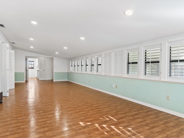 unfurnished room featuring lofted ceiling and hardwood / wood-style floors