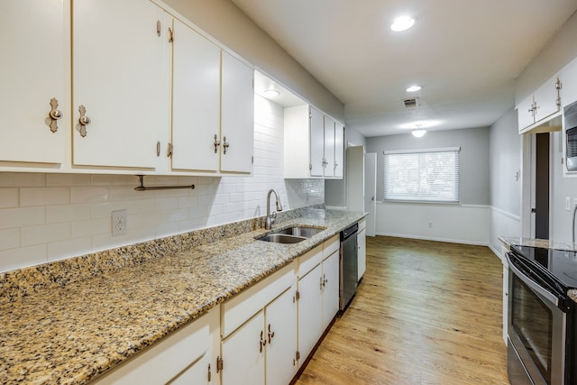 kitchen with light stone countertops, appliances with stainless steel finishes, sink, light hardwood / wood-style flooring, and white cabinetry