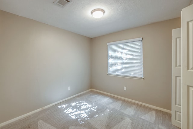 spare room with light colored carpet and a textured ceiling