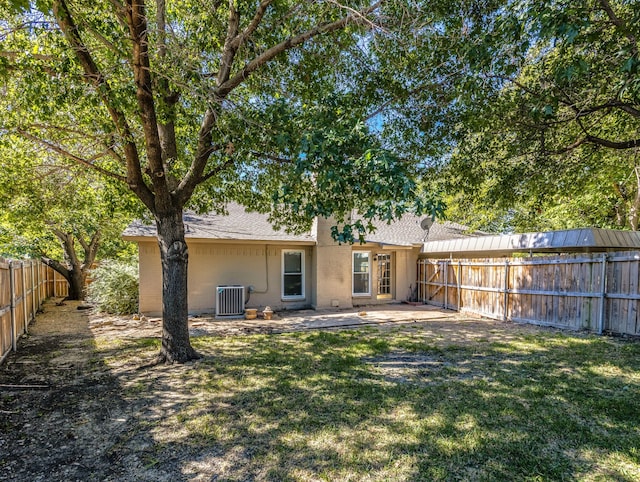 rear view of property with central AC unit and a lawn