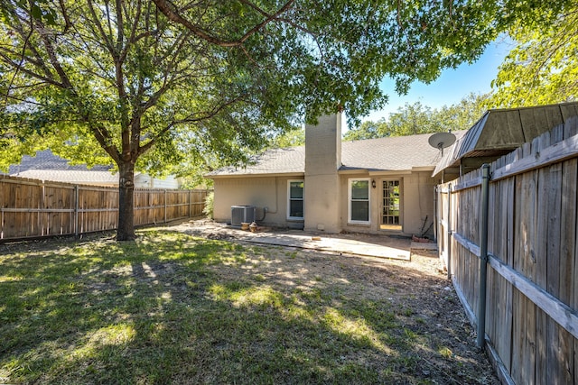 rear view of house with a lawn, cooling unit, and a patio