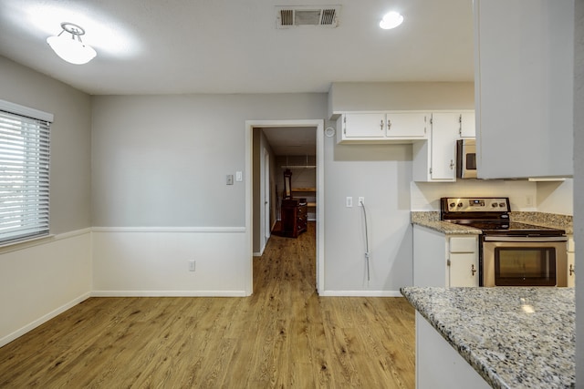 kitchen with white cabinets, light wood-type flooring, light stone countertops, and stainless steel appliances