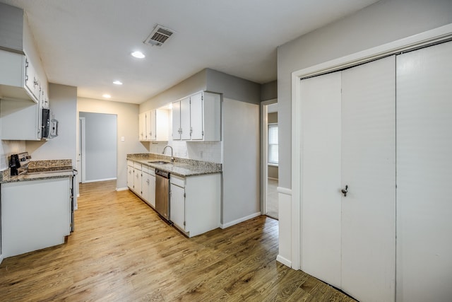 kitchen featuring white cabinets, light hardwood / wood-style floors, stainless steel dishwasher, and sink