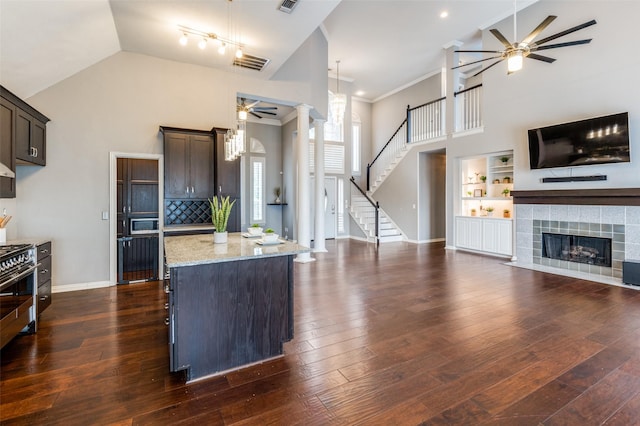 kitchen with a kitchen island, ceiling fan, light stone counters, dark brown cabinetry, and dark wood-type flooring