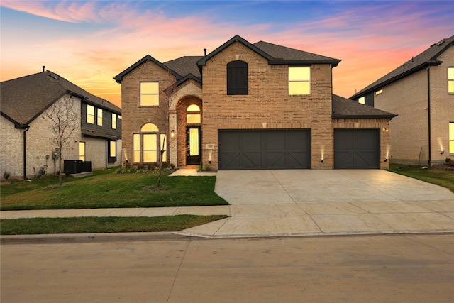 view of front facade with central air condition unit, a garage, and a lawn